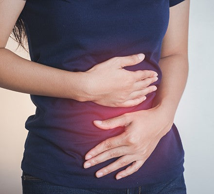 Woman holding stomach in discomfort from bloating, illustrating urgent bloating relief and quick de‑bloating before a date