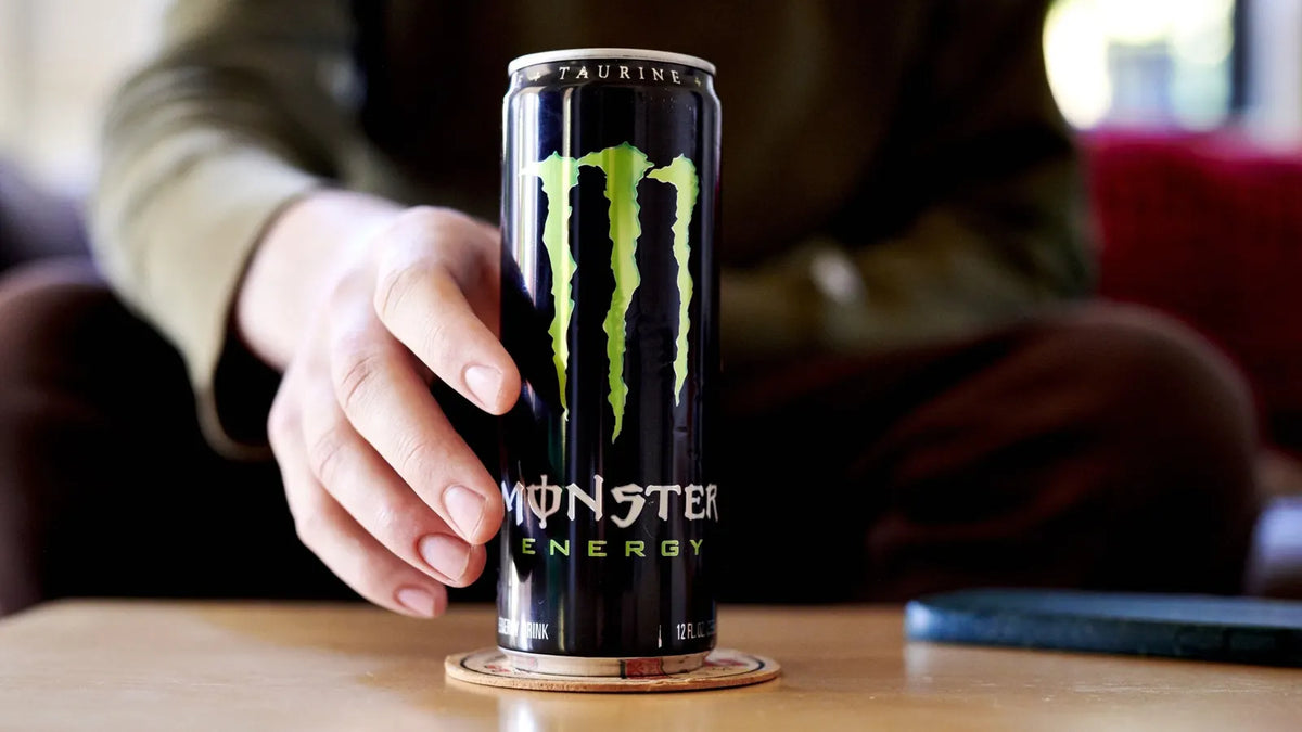 A hand holding a Monster Energy drink.